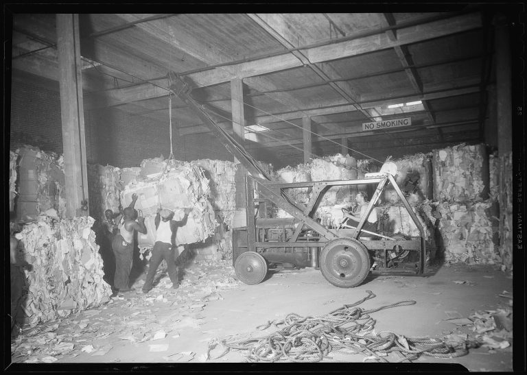 New York, New York - Longshoremen. A tractor crane is loading bales of scrap paper from warehouse of the Bush... - NARA - 518786